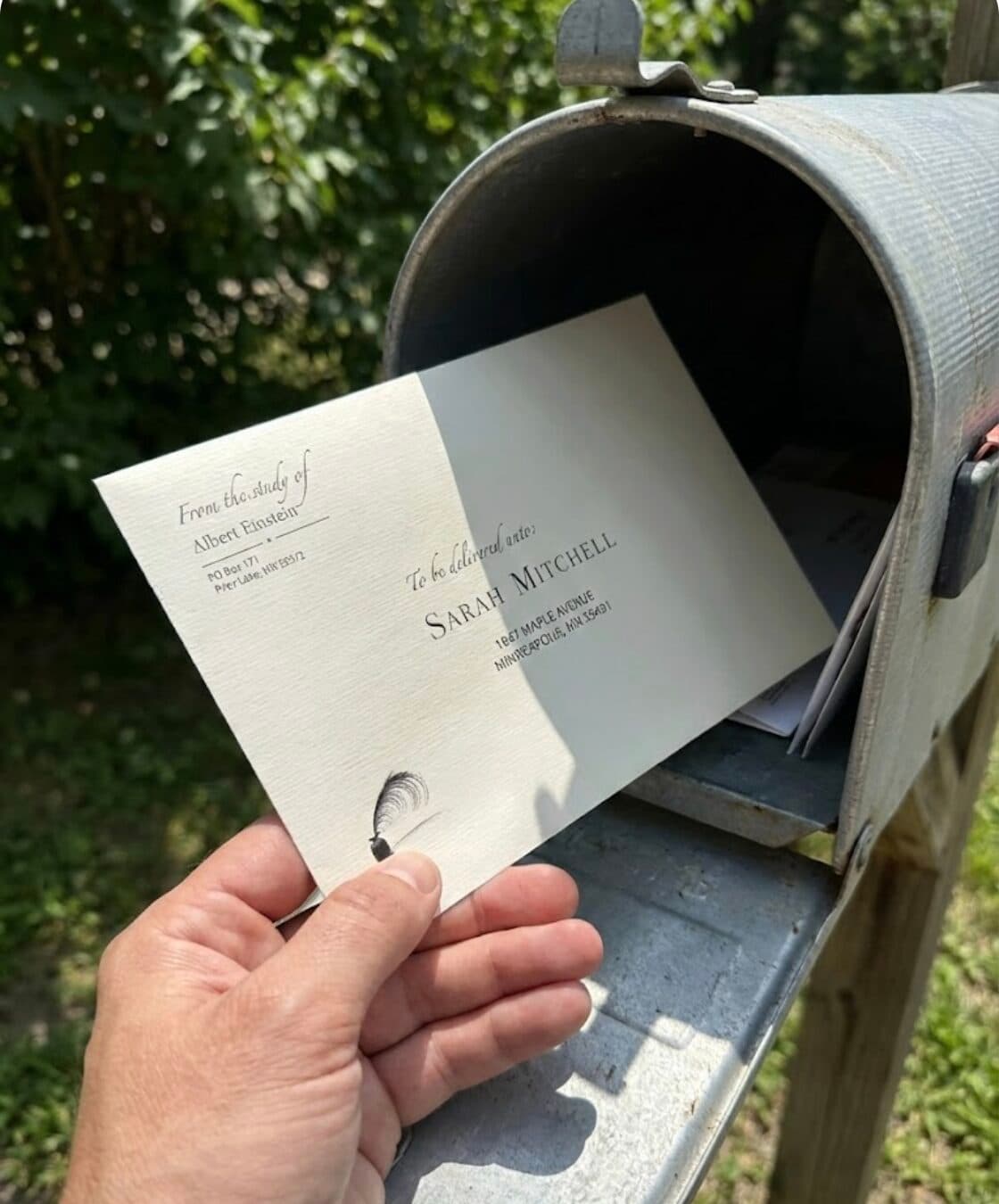 A hand pulling a handwritten letter from a real mailbox