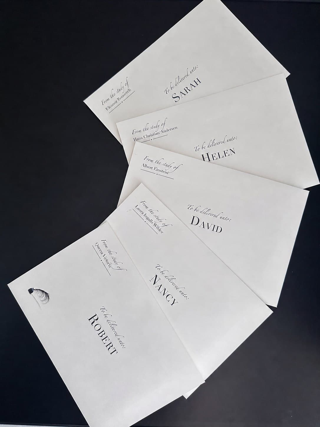 Five envelopes fanned out, each addressed by first name, each from the study of a different historical figure